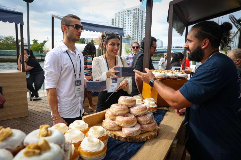 Erick Proenza, catering sales manager at The Salty Donut, right, passes out donuts to attendees during the Chase for Business event for small businesses in Miami on Wednesday, Feb. 8, 2023, at Miami Wharf. The Salty Donut was one of six local businesses that were represented because they use Chase for business banking.