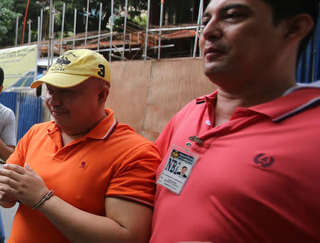 Filipino Russell Salic, 37, handcuffed, is escorted by a National Bureau of Investigation (NBI) agent after attending a hearing at the Department of Justice (DOJ) in metro Manila, Philippines August 14, 2017. Picture taken August 14, 2017. REUTERS/Stringer