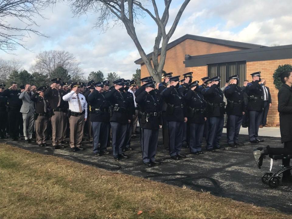 Michigan State Police troopers and other law enforcement salute MSP Sgt. Todd Leveille's casket at his funeral on Thursday, Dec. 16. 2021.