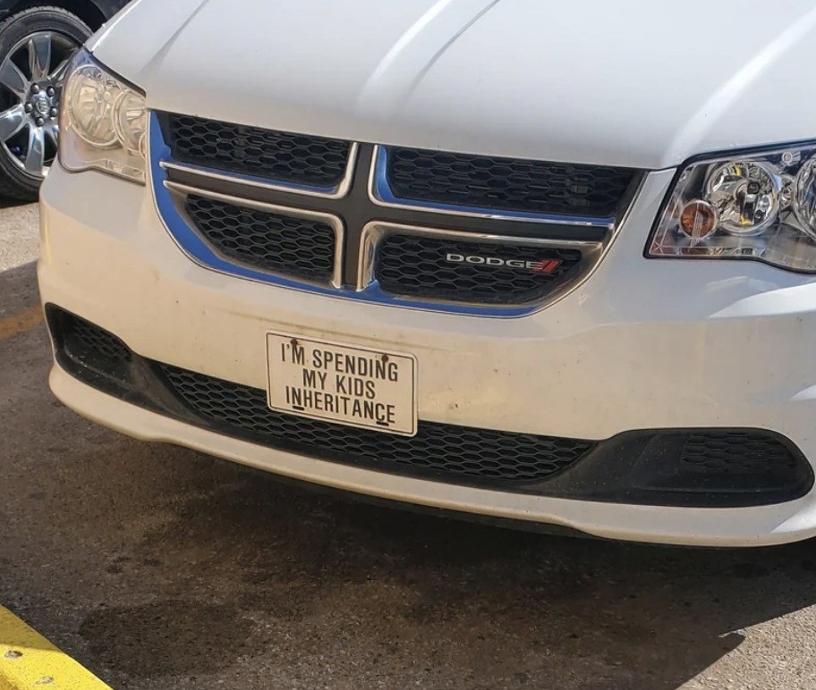 Front of a car with a license plate frame reading "I'M SPENDING MY KIDS' INHERITANCE"