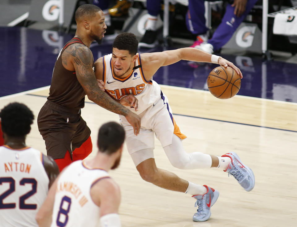 Phoenix Suns' Devin Booker muscles his way towards the basket against Portland Trail Blazers' Damien Lillard during the first half of an NBA basketball game Monday, Feb. 22, 2021, in Phoenix. (AP Photo/Darryl Webb)