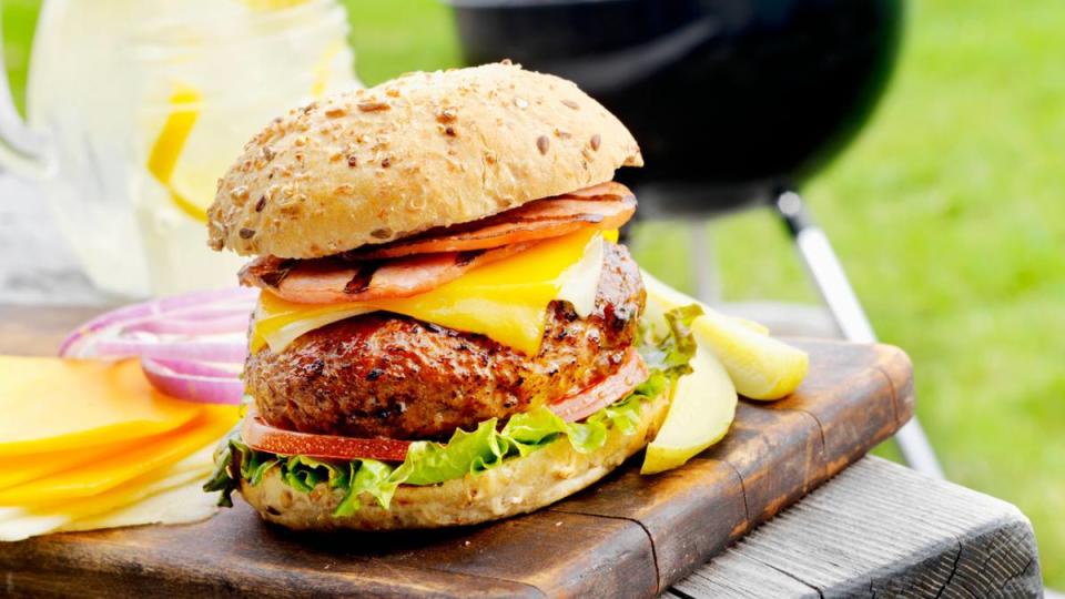 (walk off weight) A Back Bacon or Grilled Ham Cheeseburger with Lettuce,Tomato and Pickles at an Outdoor BBQ-