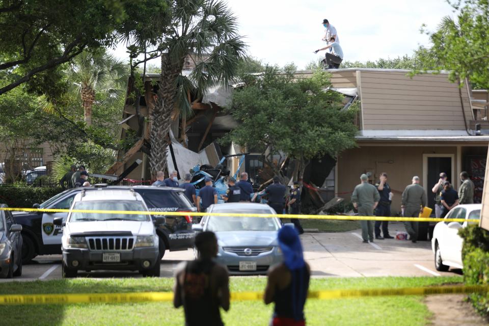 Authorities investigate the scene of a helicopter crash at an apartment complex in Houston, Saturday, May 2, 2020. Houston Police Chief Art Acevedo says the helicopter was carrying a pilot and a tactical flight officer when it went down at an apartment complex in north Houston around 2 a.m. Saturday. The cause of the crash wasn't immediately known. (Jon Shapley/Houston Chronicle via AP)