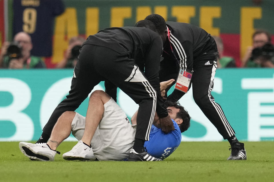 A pitch invader runs is caught while running across the field with a rainbow flag during the World Cup group H soccer match between Portugal and Uruguay, at the Lusail Stadium in Lusail, Qatar, Monday, Nov. 28, 2022. (AP Photo/Themba Hadebe)