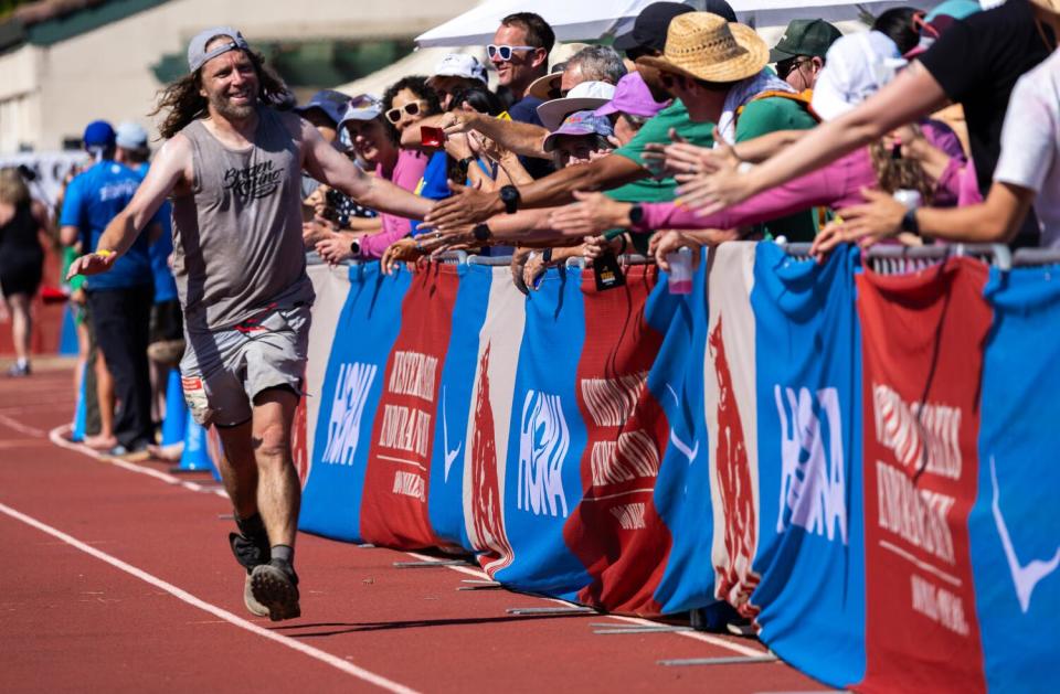 Sam Fiandaca is greeted by fans crowding the Placer High School track infield to cheer on runners.