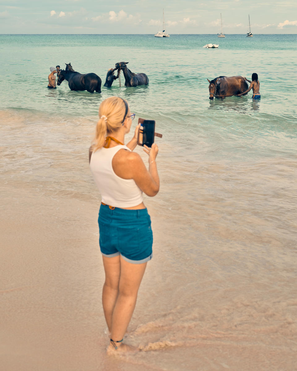 A tourist photographs caretakers bathing racehorses on Pebbles Beach. Horse racing, polo, and cricket are all commonplace in Barbados and a direct inheritance of the British colonial past.<span class="copyright">Christopher Gregory-Rivera for TIME</span>