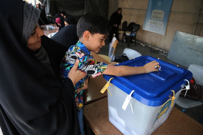 An Iranian child casts his mother’s vote during the 2024 snap presidential election at the Shah Abdol-Azim Shrine polling station in Shahre Ray, southern Tehran. Following the helicopter crash that killed conservative President Ebrahim Raisi, Iranians will vote on June 28 to elect a new president. Some 61 million Iranians are eligible to participate in the election. Rouzbeh Fouladi/ZUMA Press Wire/dpa