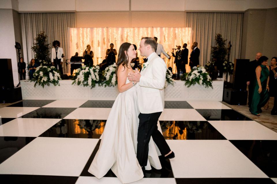 A bride and groom dance on a black-and-white checked dance floor.