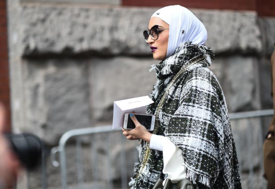 <p>This street-style star pairs her hijab with an elegant plaid scarf, poncho, and crisp white blouse. Add a pair of oversized cat-eye sunglasses and a dark lipstick to achieve this stunning look. (Photo: Getty Images) </p>