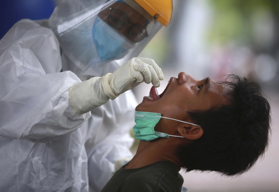 A man reacts as a medical worker collects his nasal swab samples during a mass test for the coronavirus at North Sumatra University (USU) Hospital in Medan, North Sumatra, Indonesia, Wednesday, June 2, 2021. (AP Photo/Binsar Bakkara)