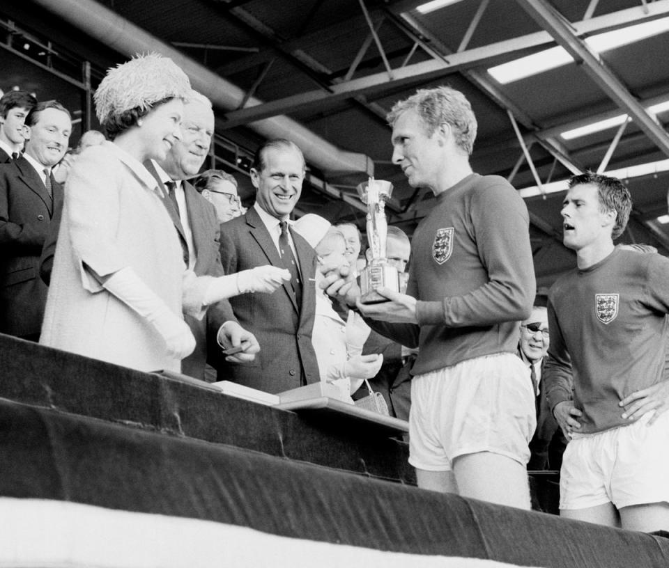 England captain Bobby Moore holds the Jules Rimet Trophy, collected from the Queen (PA)