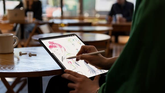 Person in a coffee shop drawing on iPad Pro