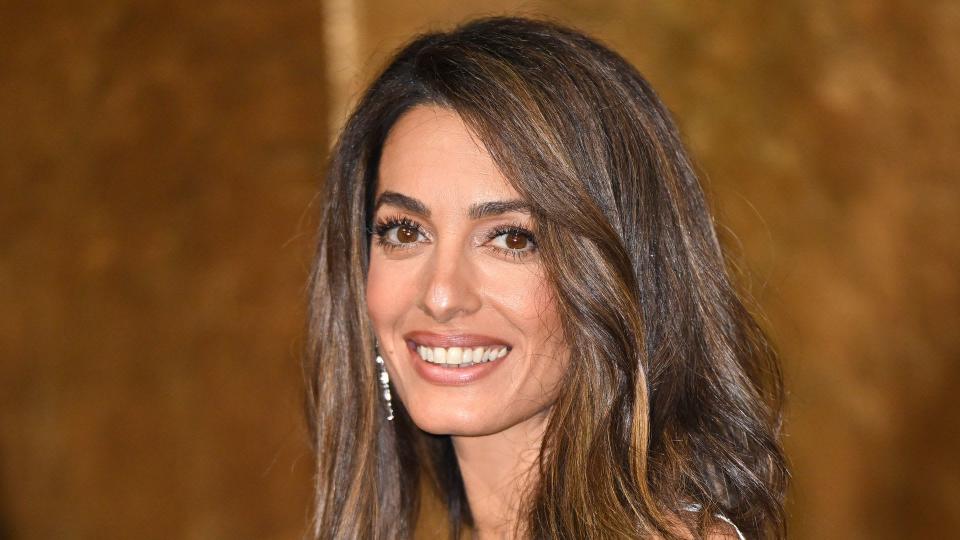 Amal Clooney smiling in a white dress