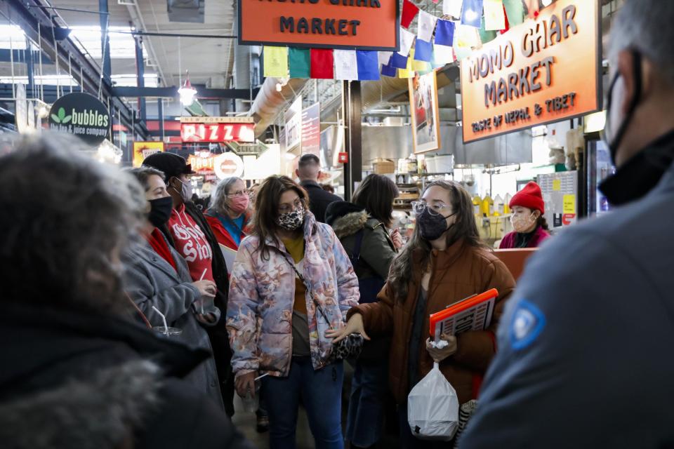 Lisa Steward, right, a guide with Columbus Food Adventures, speaks to participants about Momo Ghar Market in the North Market during a tour in Columbus, Ohio Nov. 13
