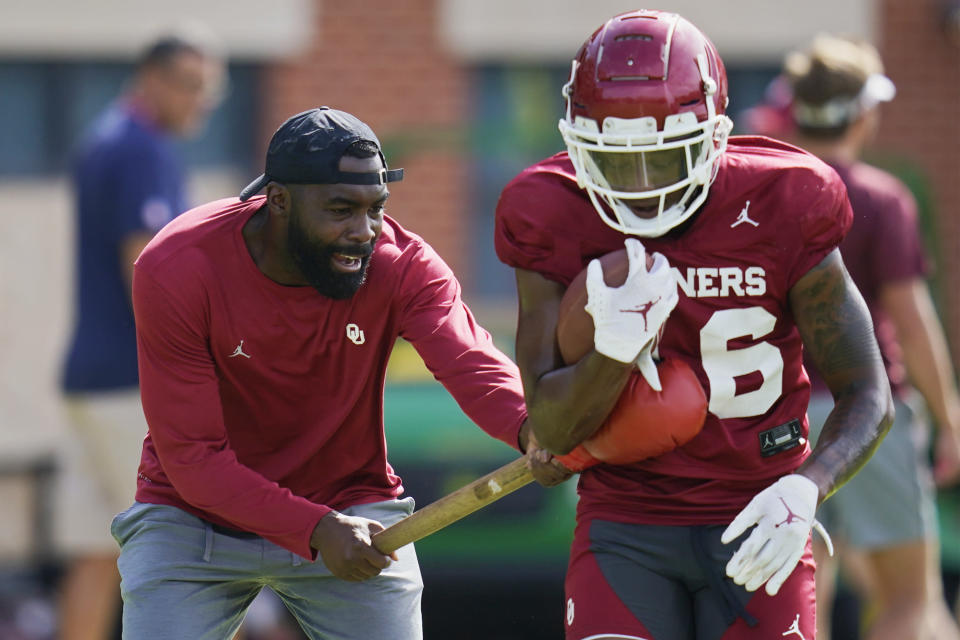 L'Damian Washington, left, runs a drill with Oklahoma wide receiver Brian Darby, right, during an NCAA college football practice, Monday, Aug. 8, 2022, in Norman, Okla. Oklahoma assistant head football coach Cale Gundy says he has resigned after using offensive language during a film session. Washington, who had been an offensive analyst, will coach receivers on an interim basis. (AP Photo/Sue Ogrocki)