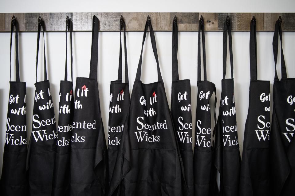 Aprons hang from a rack at Scented Wicks Candle Bar at 3109 N. Main St. Suite 102 in Hope Mills.