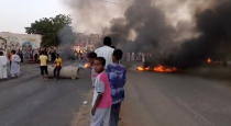 People gather around as smoke and fire are seen on the streets of Kartoum, Sudan, amid reports of a coup