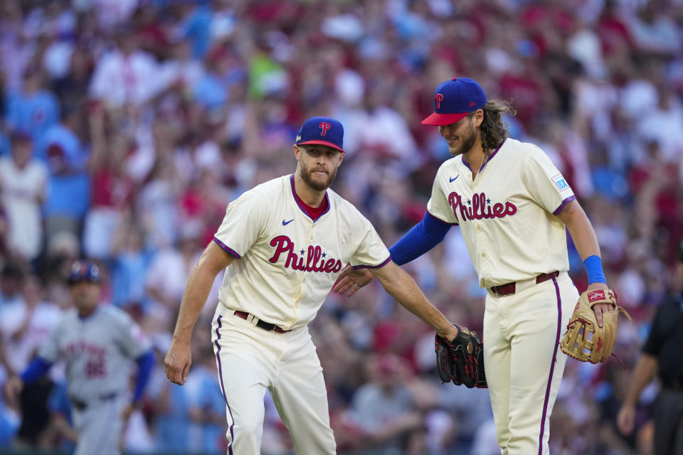 Philadelphia Phillies' Zack Wheeler, center, and Alec Bohm, react after Wheeler caught a fly out hit by New York Mets' Francisco Lindor during the third inning of Game 1 of a baseball NL Division Series, Saturday, Oct. 5, 2024, in Philadelphia. (AP Photo/Matt Slocum)