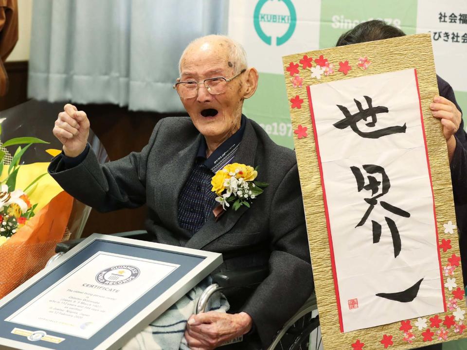 112-year-old Japanese man Chitetsu Watanabe poses next to the calligraphy he wrote after being recorded as the world's oldest living male by Guinness World Records, in Joetsu, Niigata prefecture, northern Japan, 12 February, 2020: JIJI PRESS/AFP via Getty Images