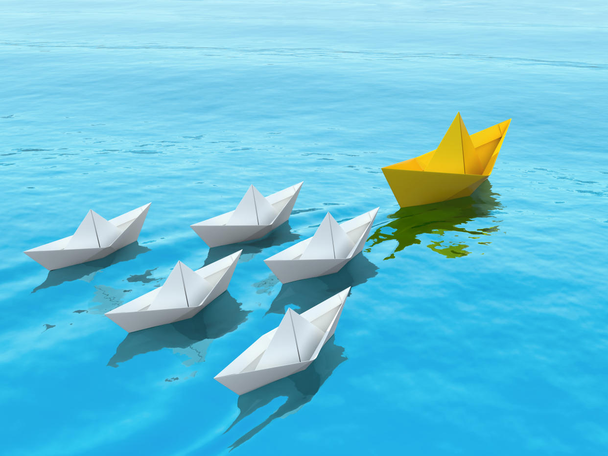 Paper ships sailing on a sea following the leader. Leadership concept 3d illustration.