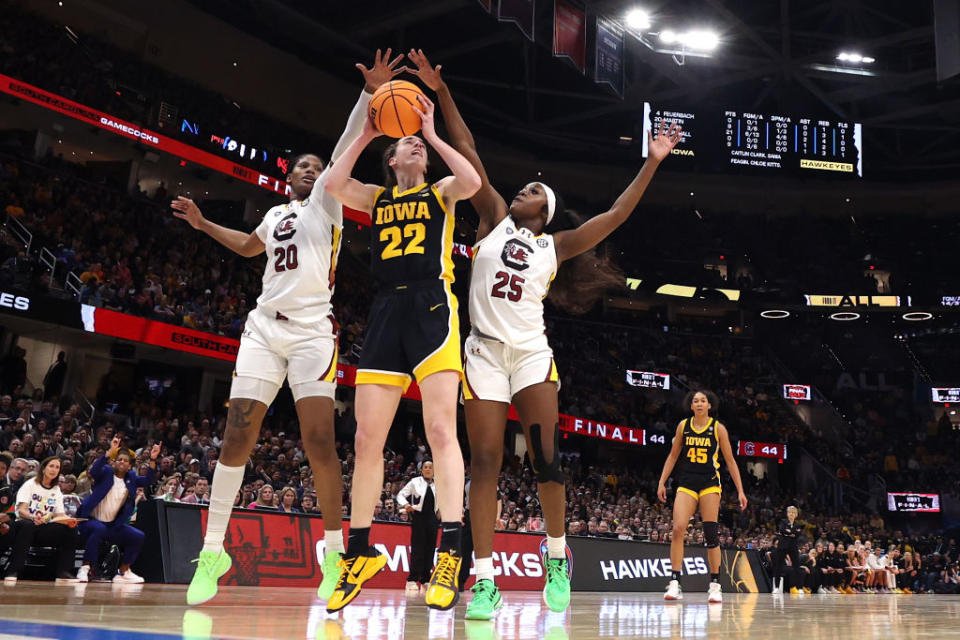 Caitlin Clark of the Iowa Hawkeyes works to shoot around Sania Feagin and Raven Johnson of the South Carolina Gamecocks in the 2024 NCAA Women's Basketball Tournament National Championship