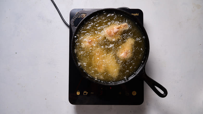chicken frying in oil in cast iron skillet