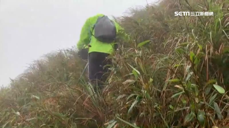 搜救員手持登山杖沿陡坡前往搜救。