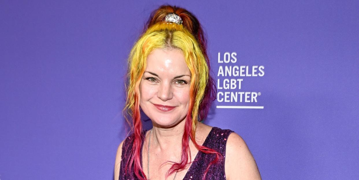 pauley perrette wearing a violet sequin dress, she has her hair in a ponytail with two half neon yellow and half cherry red strands framing her face