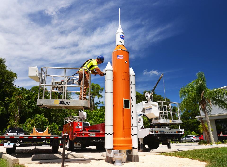 Benjamin Stanley of A Sign Co. uses a lift truck to put the finishing touches on a model Space Launch System standing about 20 feet tall Monday at Space Shirts on north Merritt Island.