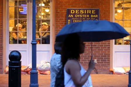 People dine at a restaurant as tourists walk down Bourbon St. during Hurricane Barry in New Orleans
