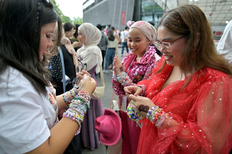 Taylor Swift fans, or Swifties, exchange friendship bracelets at the National Stadium during Swift's Eras Tour concert in Singapore