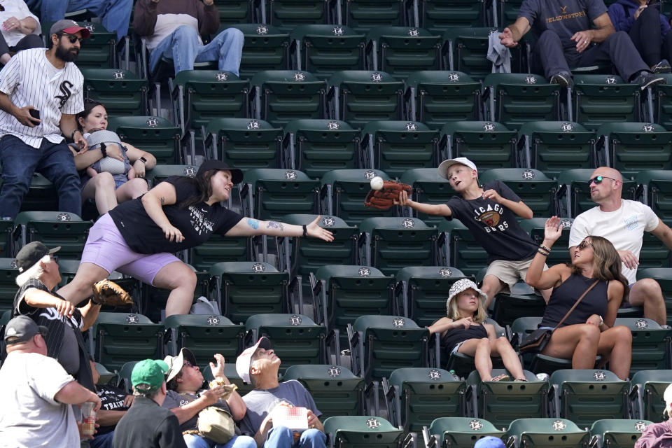 Baseball fans reach for a foul ball by Los Angeles Dodgers' Max Muncy in the upper deck of U.S. Cellular Field during the sixth inning of a baseball game between the Chicago White Sox and the Dodgers Thursday, June 9, 2022, in Chicago. (AP Photo/Charles Rex Arbogast)