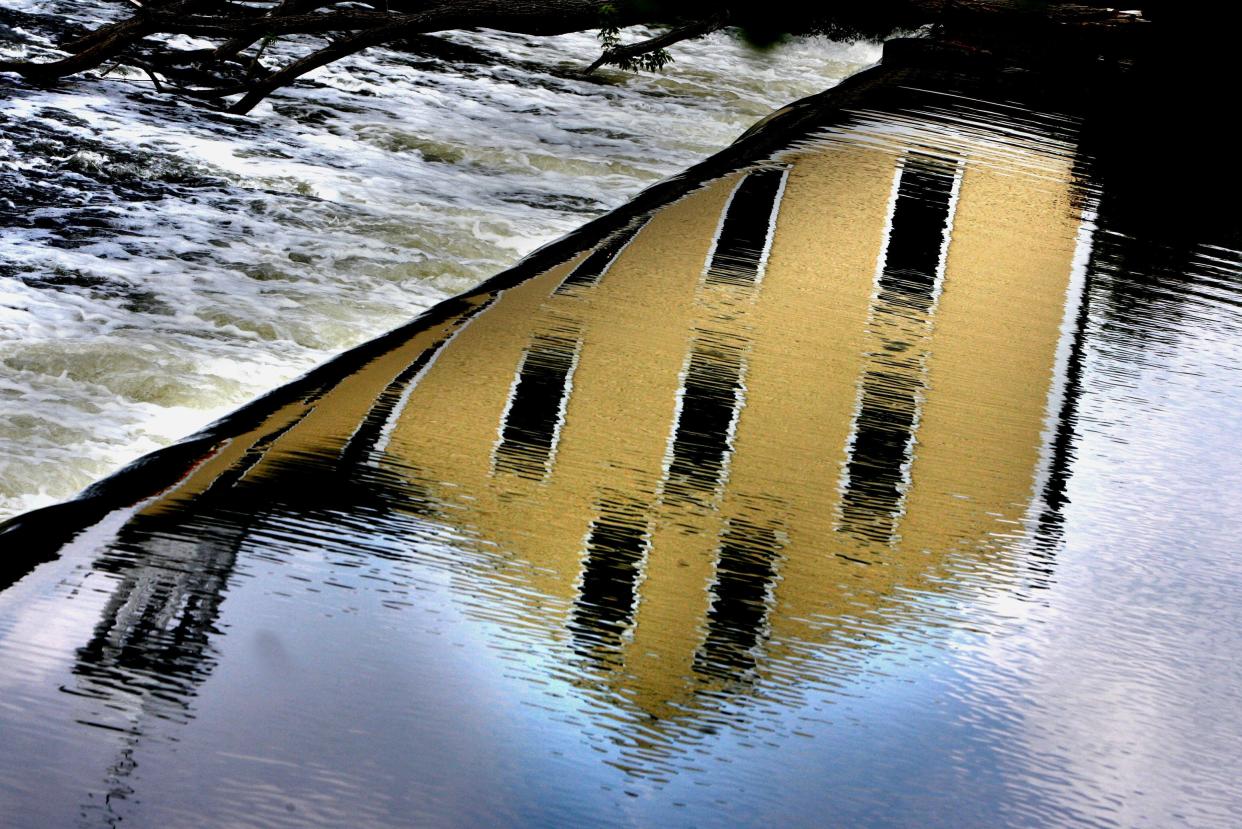 The historic Slater Mill is reflected in the cascading Blackstone River in Pawtucket.
