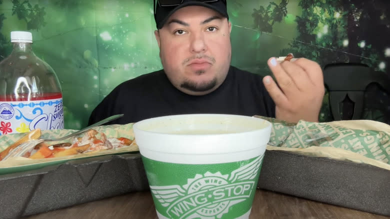 man eating chicken from a spread of fast food