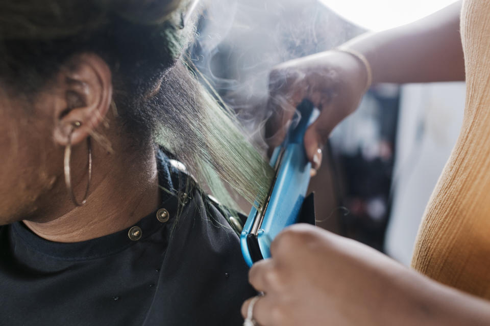 A hairstylist using a hot comb on someone's hair