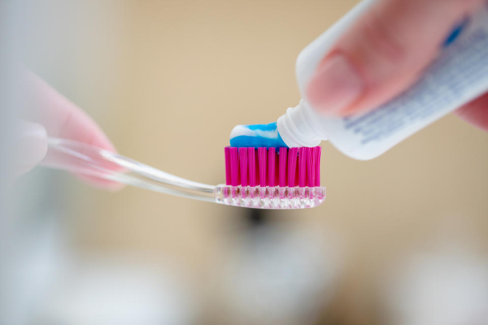 Close-up of toothbrush and a tube of toothpaste in a woman's hands