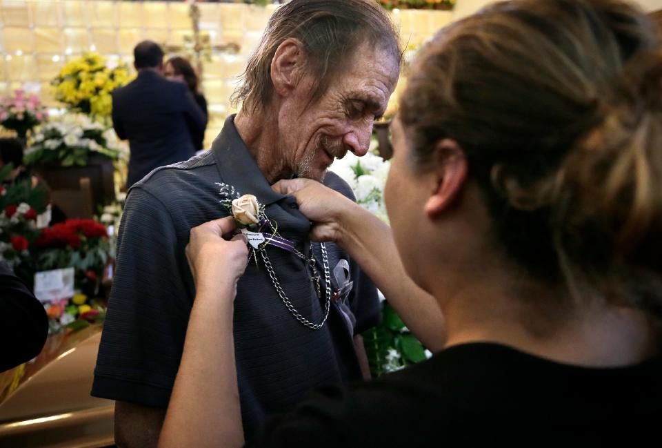 An El Pasoan pins a flower to the shirt of Antonio Basco at a prayer service  Friday, Aug. 16, 2019, for his wife Margie Reckard at La Paz Faith Center in El Paso, Texas. His wife was one of the 22 people killed in the Walmart mass shooting on Aug. 3, 2019.