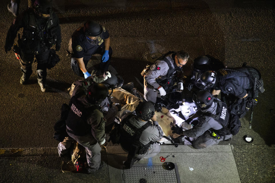 ADDS THE SHOOTING WAS FATAL - A man is treated after being shot Saturday, Aug. 29, 2020, in Portland, Ore. It wasn’t clear if the fatal shooting late Saturday was linked to fights that broke out as a caravan of about 600 vehicles was confronted by counterdemonstrators in the city’s downtown. (AP Photo/Paula Bronstein)