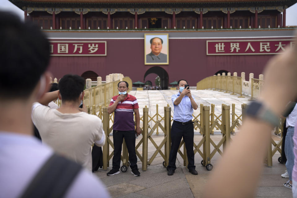 Visitors wearing face masks pose for photos near a large portrait of Chinese leader Mao Zedong on Tiananmen Gate near Tiananmen Square in Beijing, Saturday, Sept. 18, 2021. China's "zero tolerance" strategy of trying to isolate every case and stop transmission of the coronavirus has kept kept the country where the virus first was detected in late 2019 largely free of the disease. (AP Photo/Mark Schiefelbein)