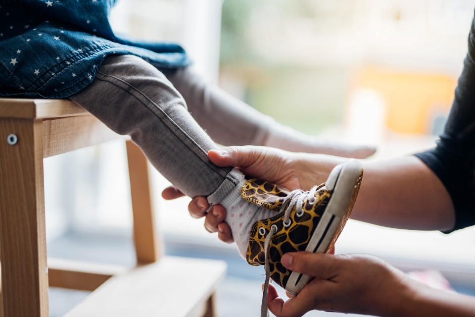 Hands putting a shoe on a little kid's foot