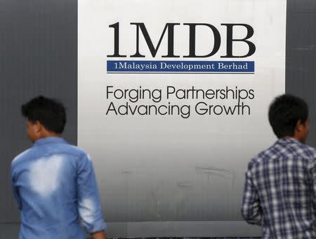 Men walk past a 1 Malaysia Development Berhad (1MDB) billboard at the funds flagship Tun Razak Exchange development in Kuala Lumpur, Malaysia, March 1, 2015. REUTERS/Olivia Harris