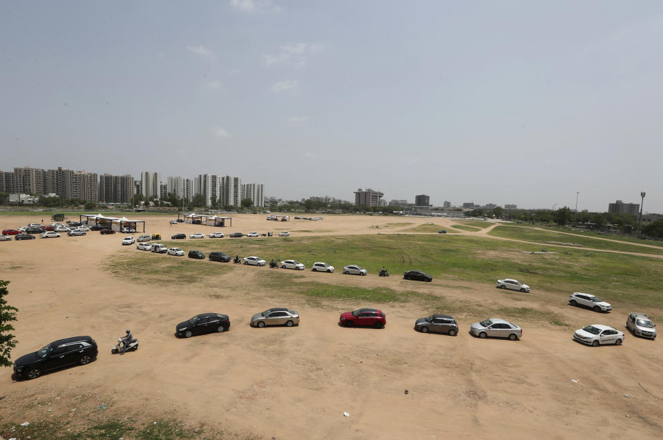 FILE - In this May 28, 2021, file photo, motorists line up to receive Covishield, the Oxford-AstraZeneca vaccine for COVID-19 at a drive-in vaccination facility in Ahmedabad, India. Starting June 21, 2021, every Indian adult can get a COVID-19 vaccine dose for free that was purchased by the federal government. The policy reversal announced last week ends a complex system of buying vaccines that worsened inequities in accessing vaccines. India is a key global supplier of vaccines and its missteps have left millions of people waiting unprotected. The policy change is likely to address inequality but questions remain and shortages will continue. (AP Photo/Ajit Solanki, File)