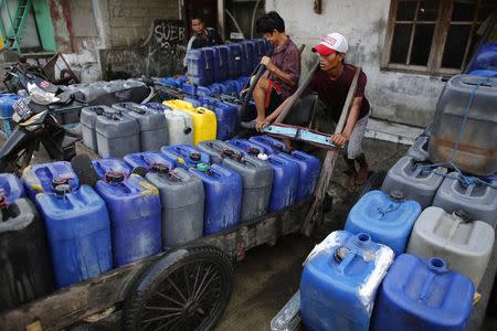 Delivery men fill up plastic jerry cans with water before setting off to deliver them to residents who increasingly have no access to piped or well water in Pluit, north Jakarta, September 30, 2014. REUTERS/Darren Whiteside