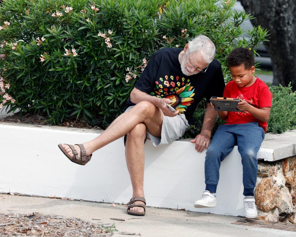 Juneteenth ceremony attendees sit on a low wall at last year’s event outside Daytona Beach City Hall.