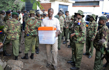 An electoral official walks past riot policemen as he carries ballot boxes to be used by members of the Orange Democratic Movement (ODM) for their party primary in the Kenya's west city of Kisumu April 25, 2017. REUTERS/Moses Eshiwani