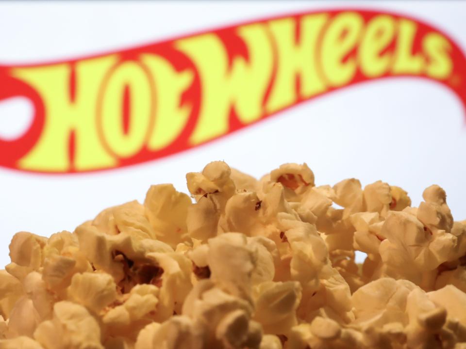 a tub of popcorn in front of a hot wheels logo on a screen