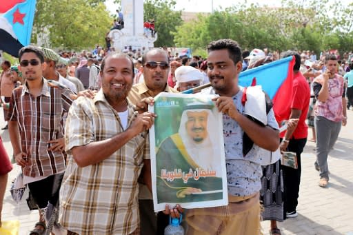 Men hold a portrait of Saudi Arabia's King Salman as Yemeni separatist supporters wave flags of the former South Yemen