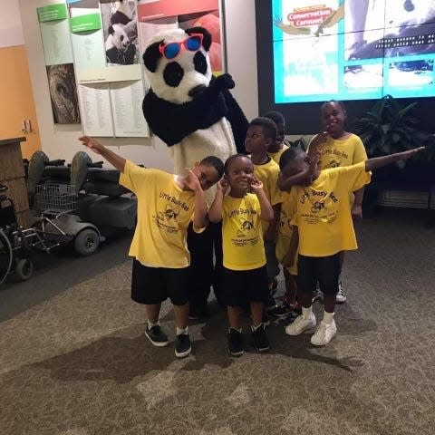 Antwon Hines, dressed as Pantwon the panda, dabs with a group of children inside the Smithsonian National Zoo's visitor center in Washington, D.C.