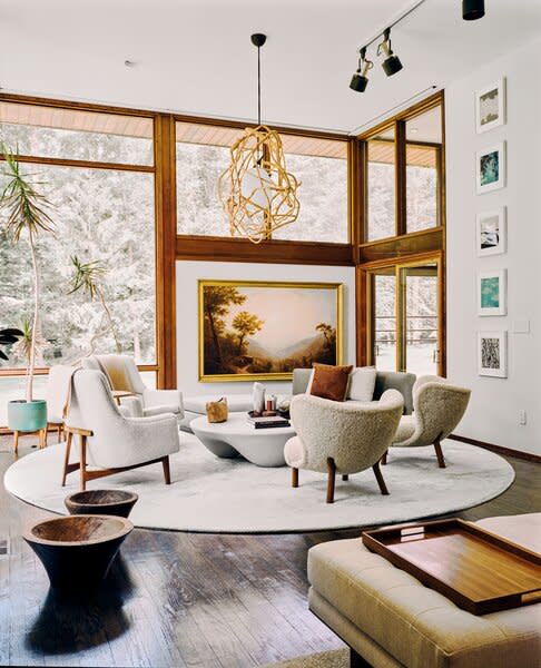 In the living room, soft-hued seating arranged in a circle is perfect for entertaining. On the far wall, Sunrise Over the Hudson, by Erik Koeppel, competes with the stunning scenery outside. 