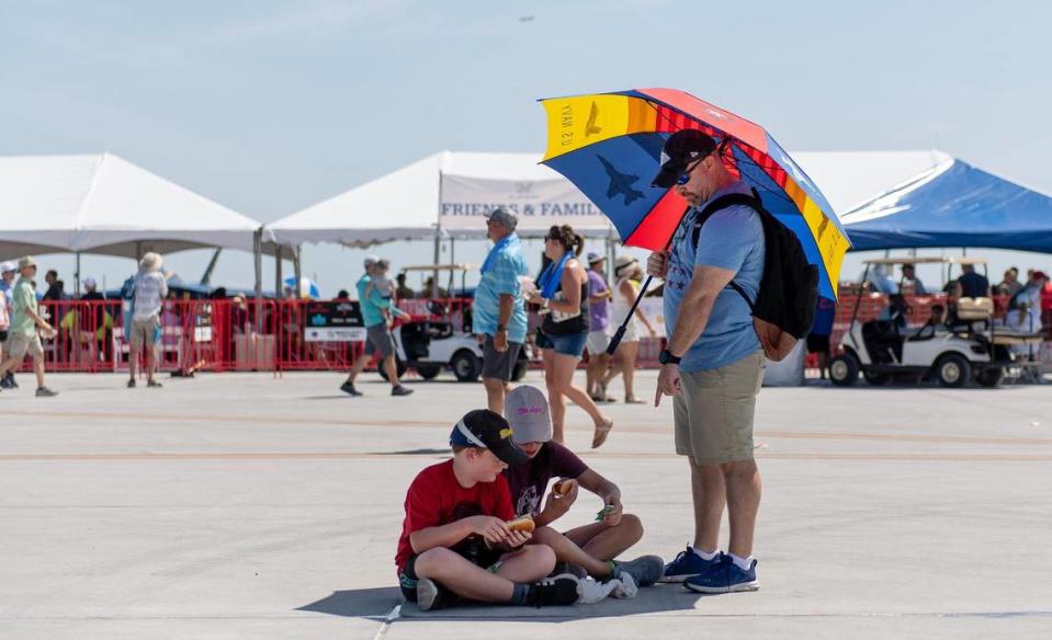 Brian McConnell shades his daughter Addie and son Chris as they eat during the Garmin KC Air Show on Saturday, Aug. 19, 2023, in New Century.